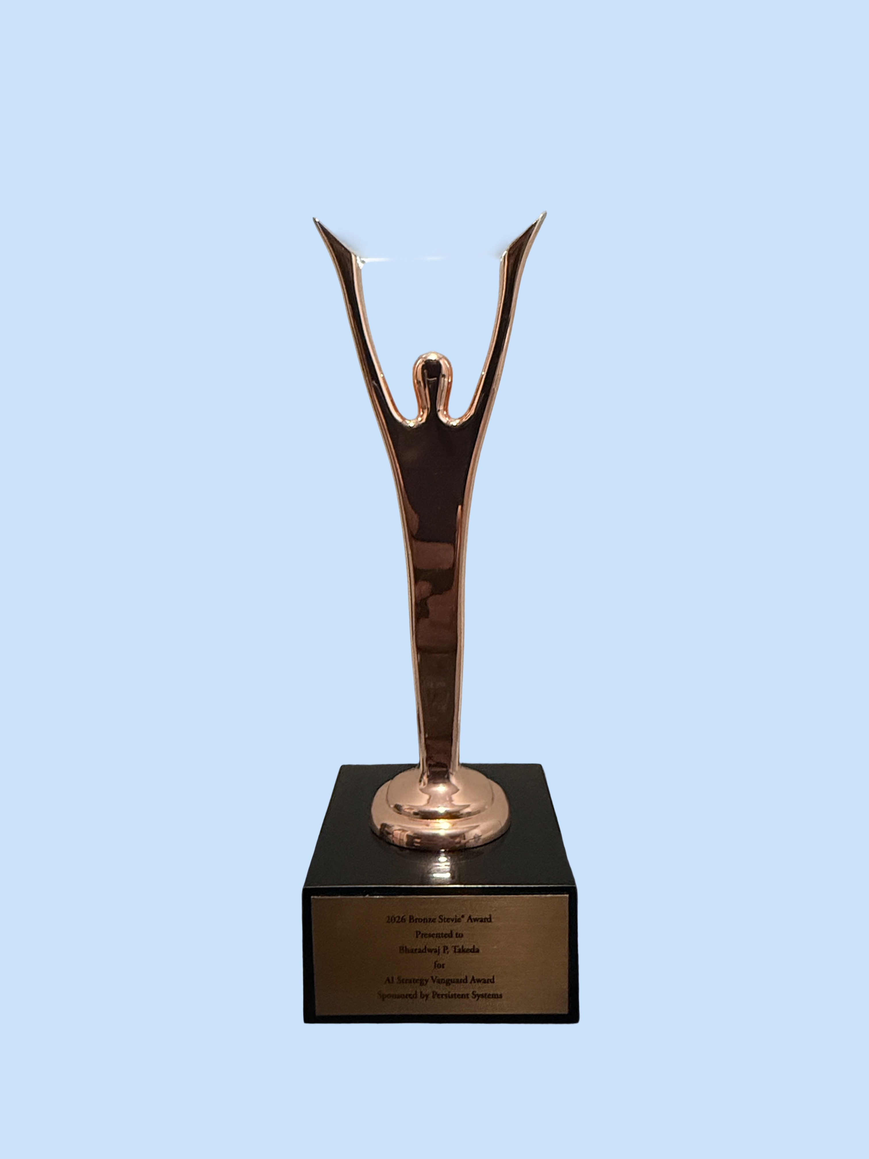 The 2026 Bronze Stevie Award trophy for the AI Strategy Vanguard Award, photographed on a desk.